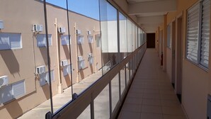 A corridor with a glass railing, air conditioning units, and a tiled floor. - Cristal Palace Inn (Lins)