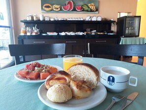 Un desayuno con un plato de comida, un vaso de jugo de naranja y una taza de café sobre una mesa.