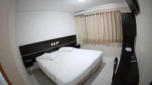 A hotel room with a bed, a TV mounted on the wall, an air conditioning unit, and a window with curtains. - Cristal Palace Inn (Lins)