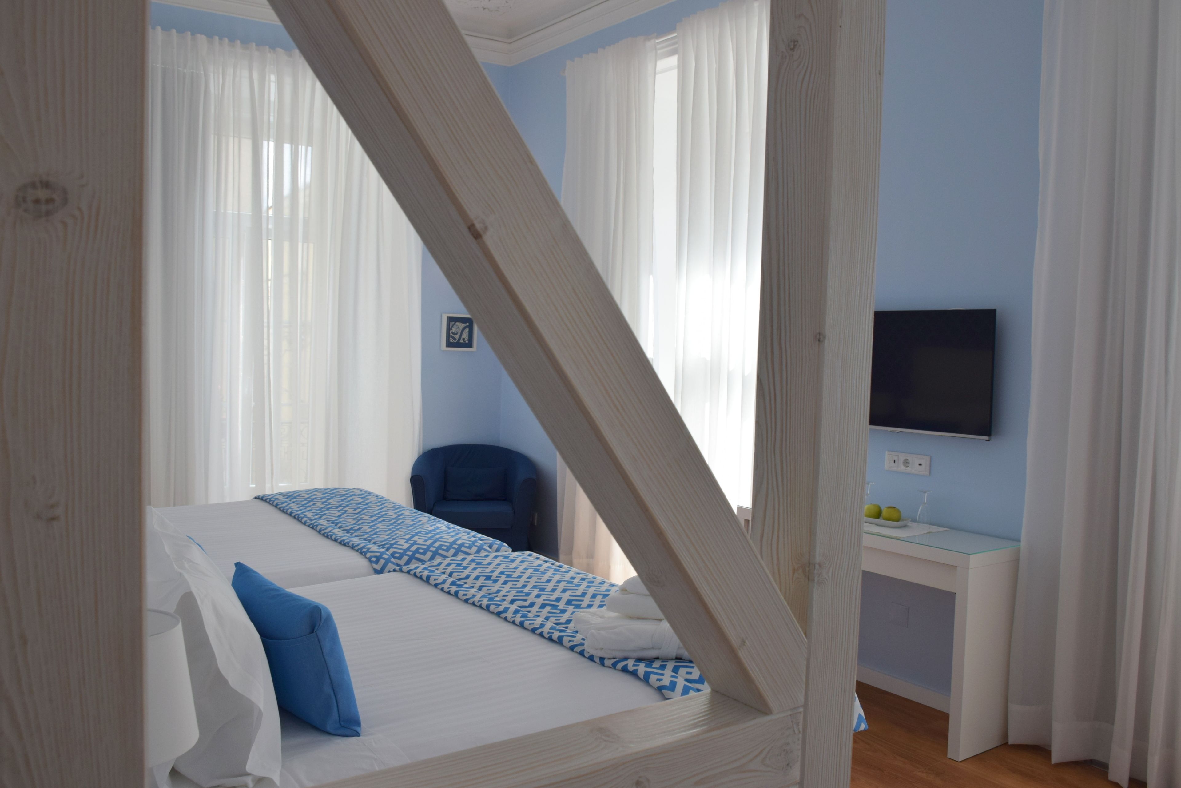 Un dormitorio con cama, una silla, un escritorio y televisión.
