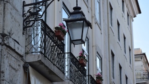 A building with a balcony featuring wrought iron railings and potted plants.