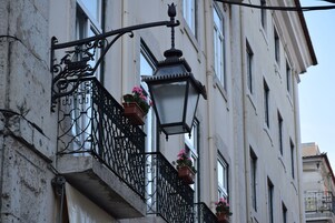Een gebouw met een balkon, voorzien van smeedijzeren hekken en bloempotten.