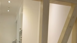 A kitchen with white cabinets, a wooden chair, and a countertop with a coffee machine.