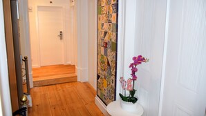 A hallway with a wooden floor, a white door, and a colorful tile wall.