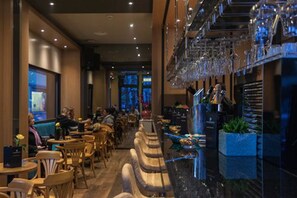 A restaurant with a bar area, seating arrangements, and a view of the street outside. - Plaza Hotel (Winterthur)