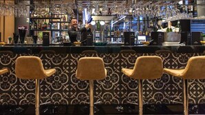 A bar area with a bartender, bar counter, and three bar stools. - Plaza Hotel (Winterthur)