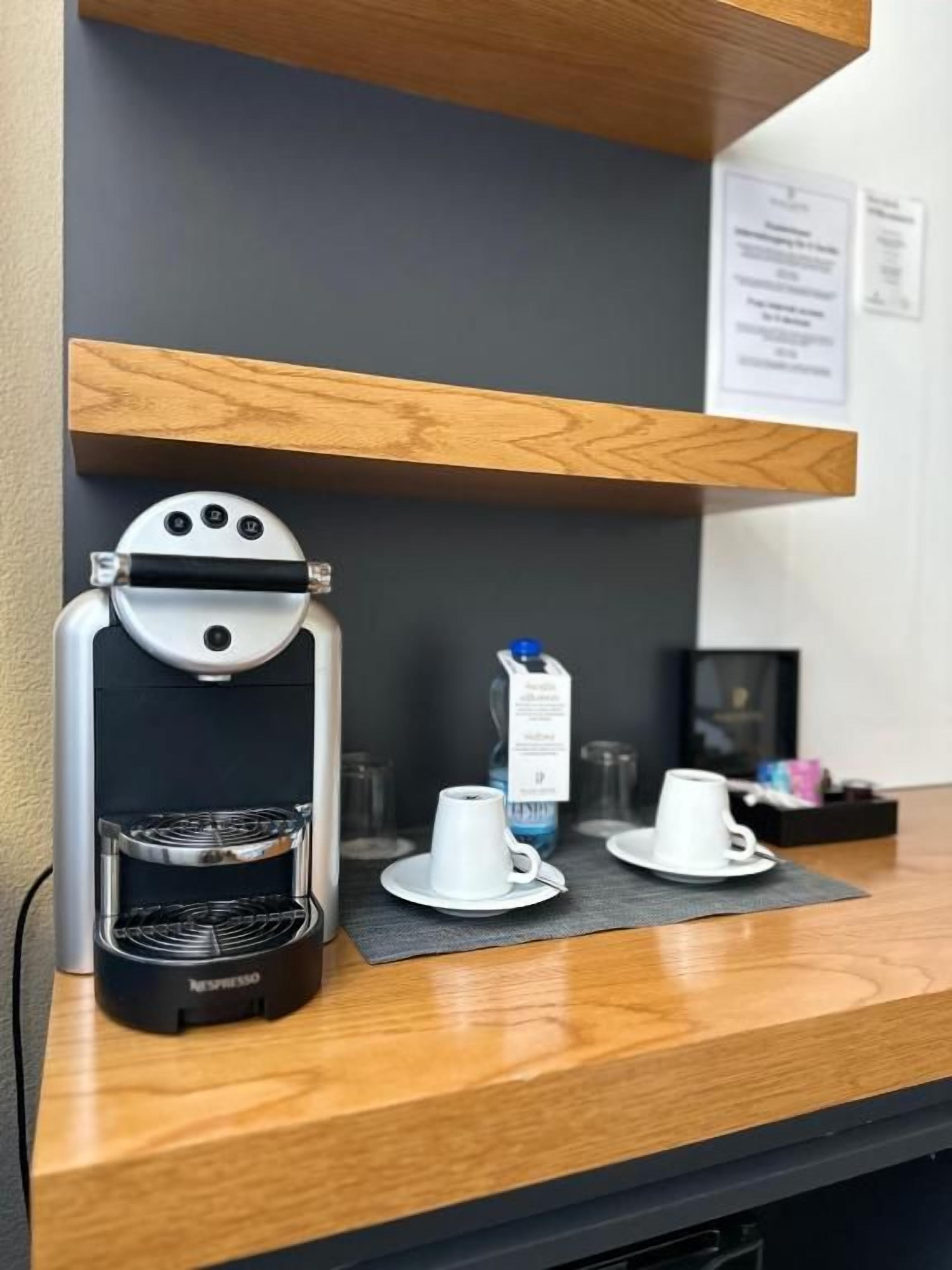 Una cafetera sobre una encimera con un estante de madera encima.