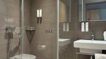 A modern bathroom with a glass-enclosed shower, a white sink, and a mirror above the sink.