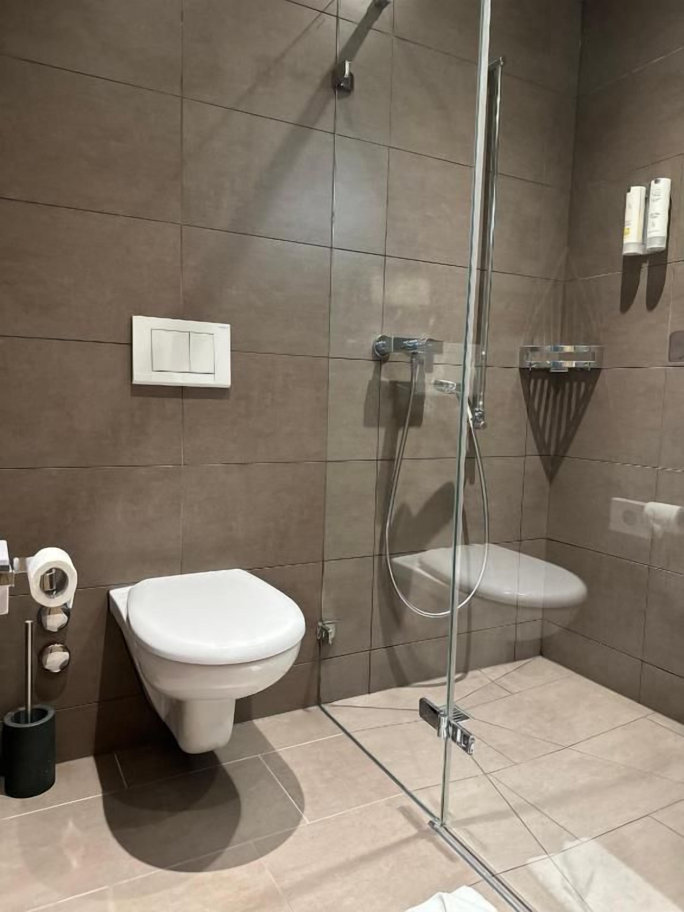 Et moderne badeværelse med bruseniche i glas, toilet og bidet.