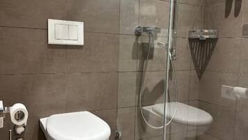 Et moderne badeværelse med bruseniche i glas, toilet og bidet.