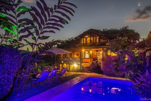 Un espace extérieur bien éclairé, doté d’une piscine, de chaises longues et d’un bâtiment à plusieurs étages.