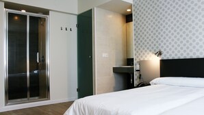 Habitació d'hotel amb llit, un vestidor i una zona de dutxa.