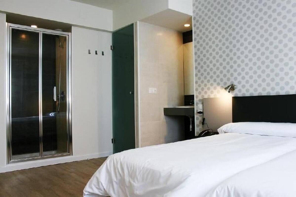 A hotel room with a bed, a walk-in closet, and a shower.