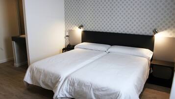 A neatly made double bed with white linens, a modern headboard, and two bedside lamps.