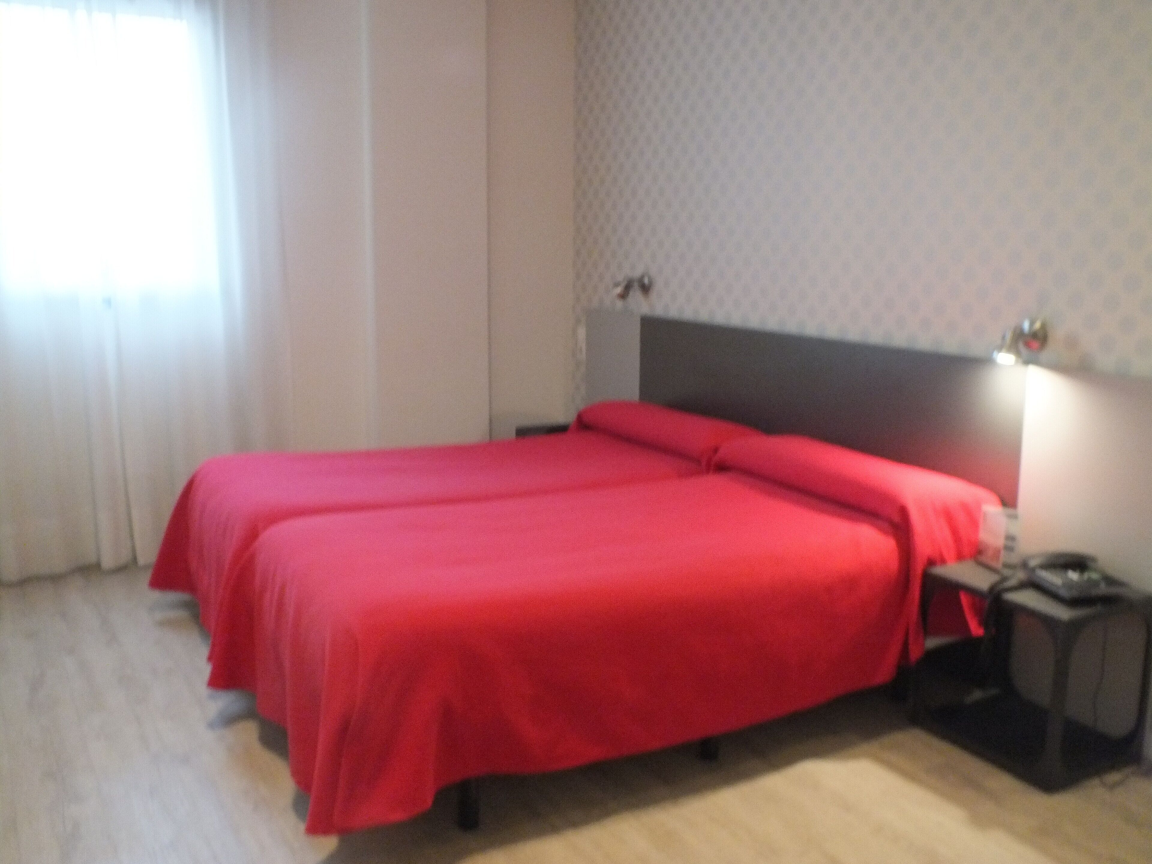 Una camera d'albergo con un letto matrimoniale, un comodino e un tavolino.