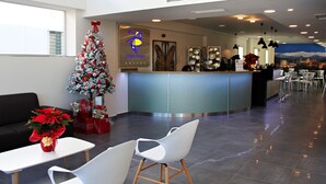 Un vestíbul d'hotel amb una taquilla d'accés, un arbre de Nadal i zones d'estar.