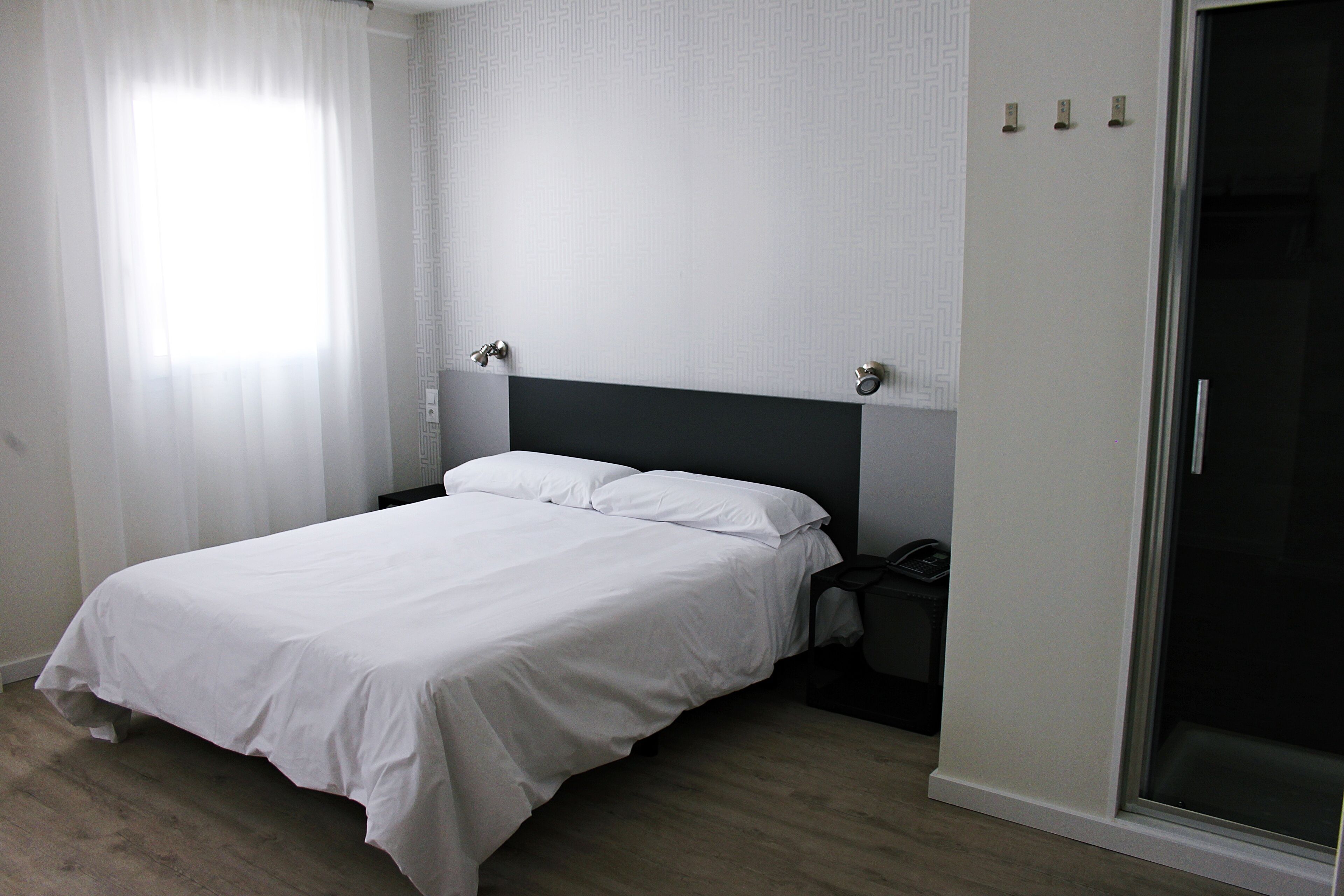 Un dormitorio con cama, mesita de noche, armario y puerta corredera.
