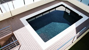 Una piscina rectangular amb un videt blanc sobre un solàrium.