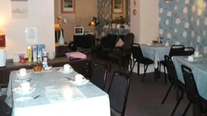 A dining area with tables set for a meal, chairs, a television, and a mirror on the wall. - Abbey Lodge (London)