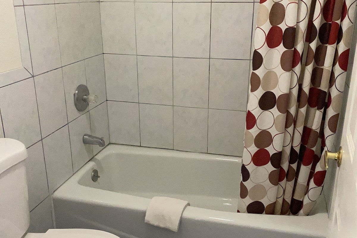A bathroom with a toilet, bathtub, and shower curtain.