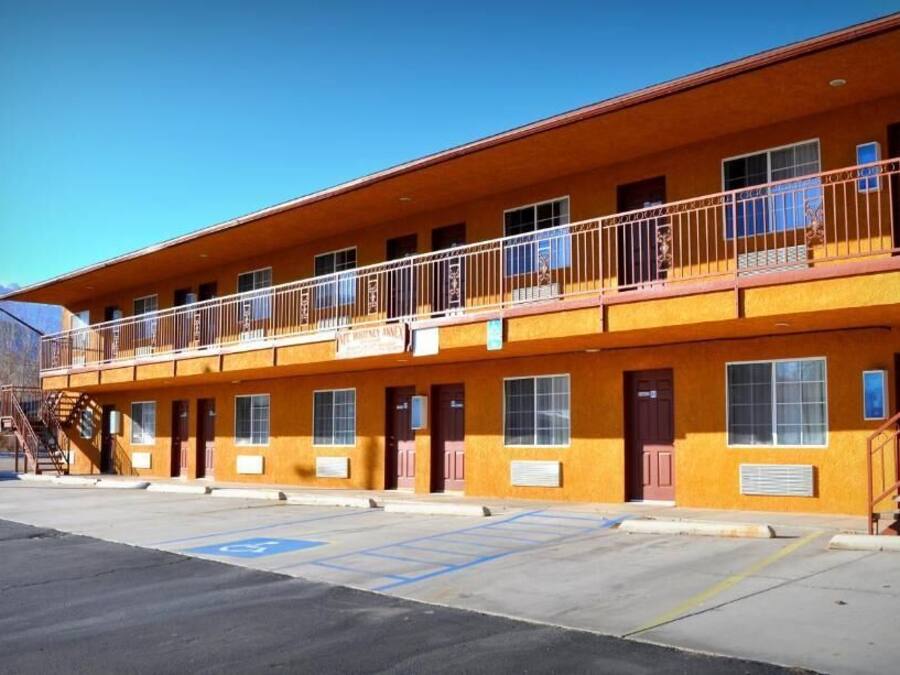 A two-story motel with a flat roof, multiple windows, and a balcony on the upper floor.