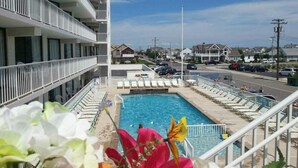 Hotel med swimmingpool, flere balkoner og udsigt til gaden.