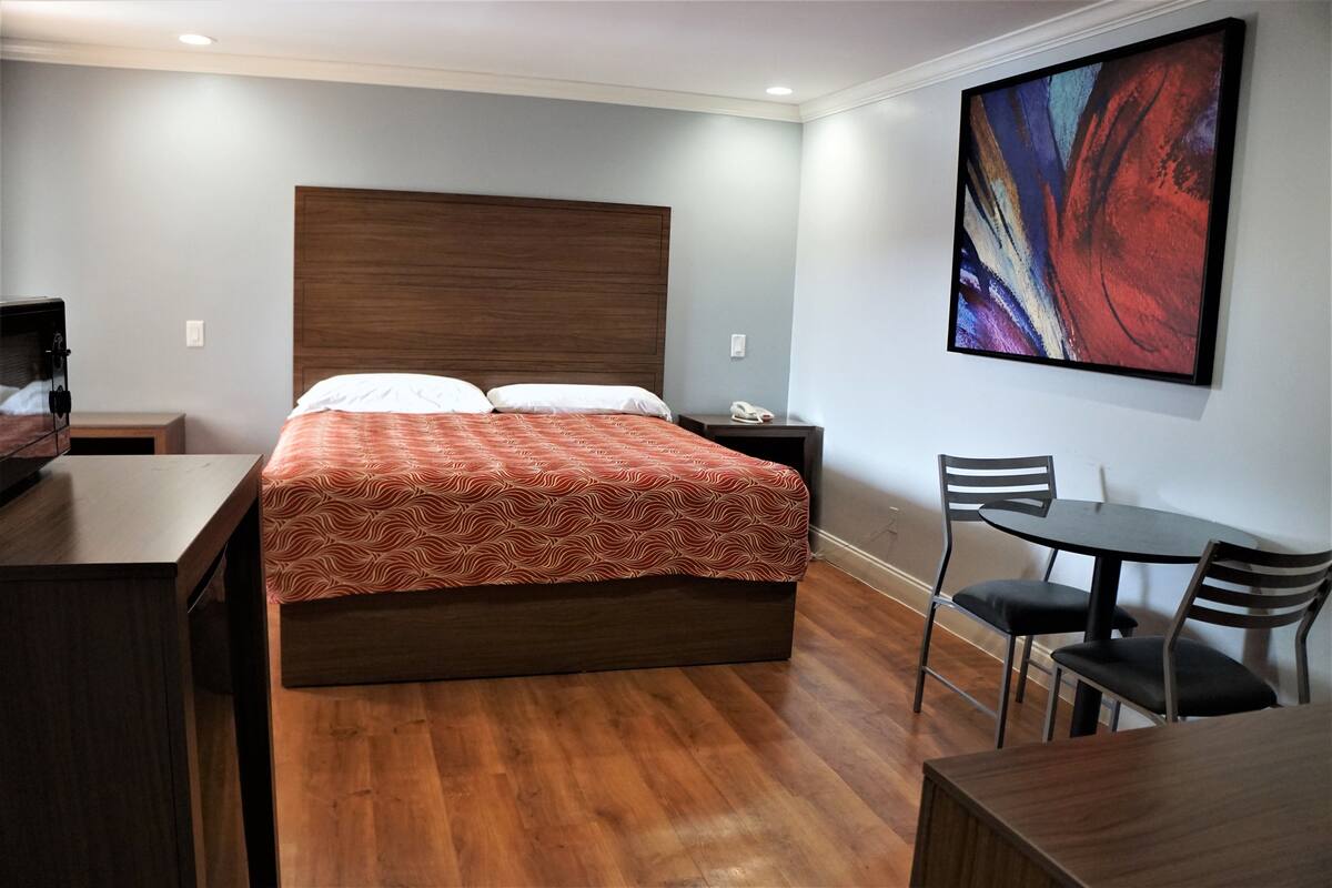 Ein Hotelzimmer mit einem hölzernen Bett, einem Schreibtisch, einem Stuhl und einem Tisch.