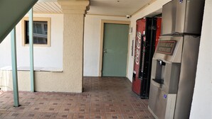 A corridor with a brick floor, a green door, and a Coca-Cola refrigerator. - Palace Inn - Antoine (Houston)