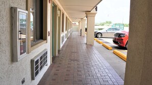 A covered walkway with a brick floor, columns, and a row of windows. - Palace Inn - Antoine (Houston)