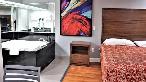 A modern bathroom with a large mirror, a black sink, and a wooden nightstand. - Palace Inn - Antoine (Houston)