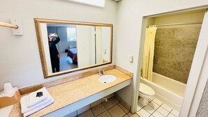 Un baño con lavamanos, espejo y ducha.
