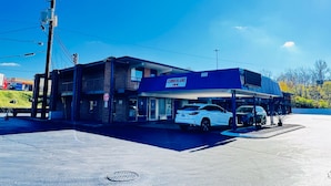 Un edificio de dos pisos con un letrero que dice 'Cumberland Inn', un estacionamiento y un automóvil blanco estacionado al frente.