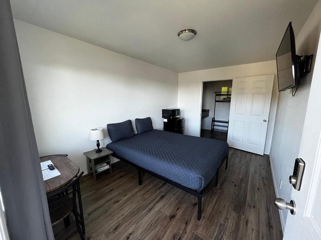 A room with a bed, a desk, a lamp, and a television.