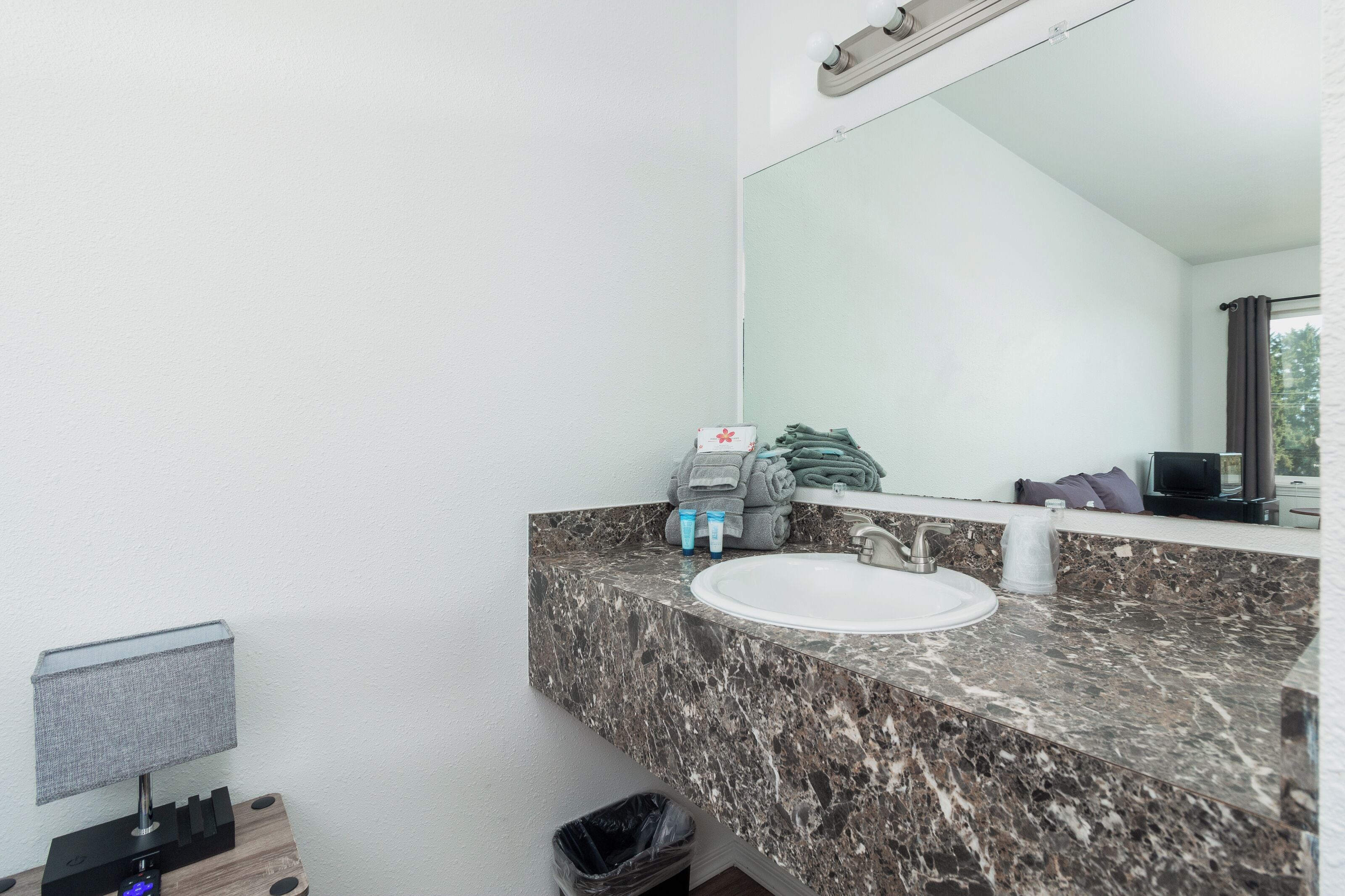 Een badkamer met een marmeren aanrechtblad, een wastafel, een spiegel en een handdoekhouder.