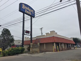 A Budget Inn sign, a building with a red roof, and a parking lot.