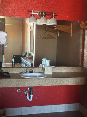 A bathroom with a sink, mirror, and towel rack.