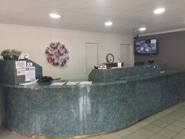 A reception area with a marble counter, a clock, a television, and a wreath on the wall.