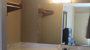Une salle de bain avec un comptoir en marbre blanc, un lavabo, un miroir et un luminaire placé au-dessus du miroir.