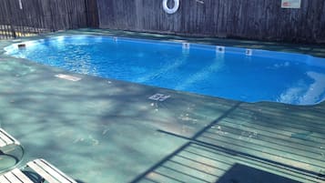 Une piscine avec une terrasse en bois et une bouée de sauvetage.