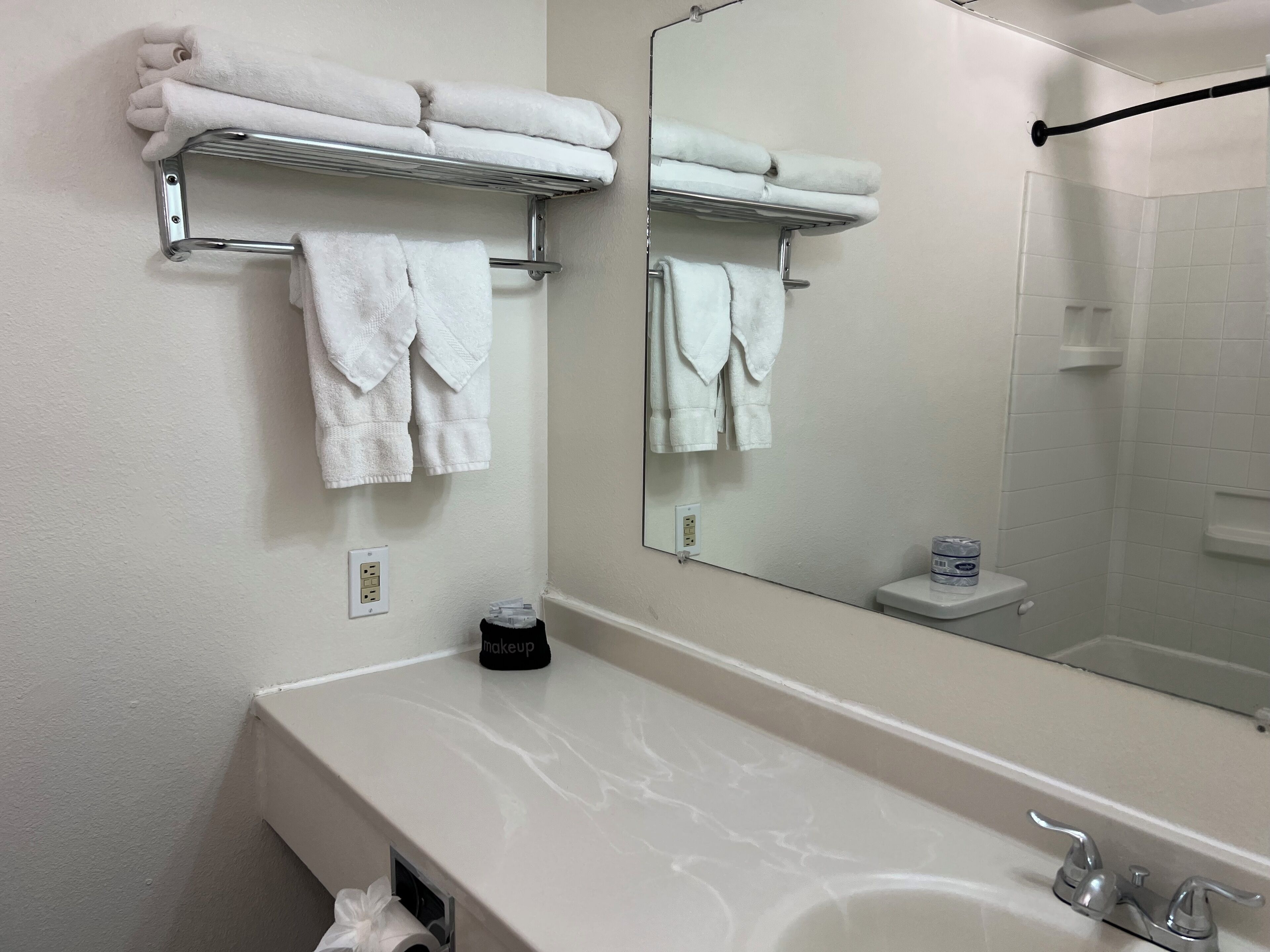 A bathroom with a white sink, a mirror, and two towel racks with folded towels.