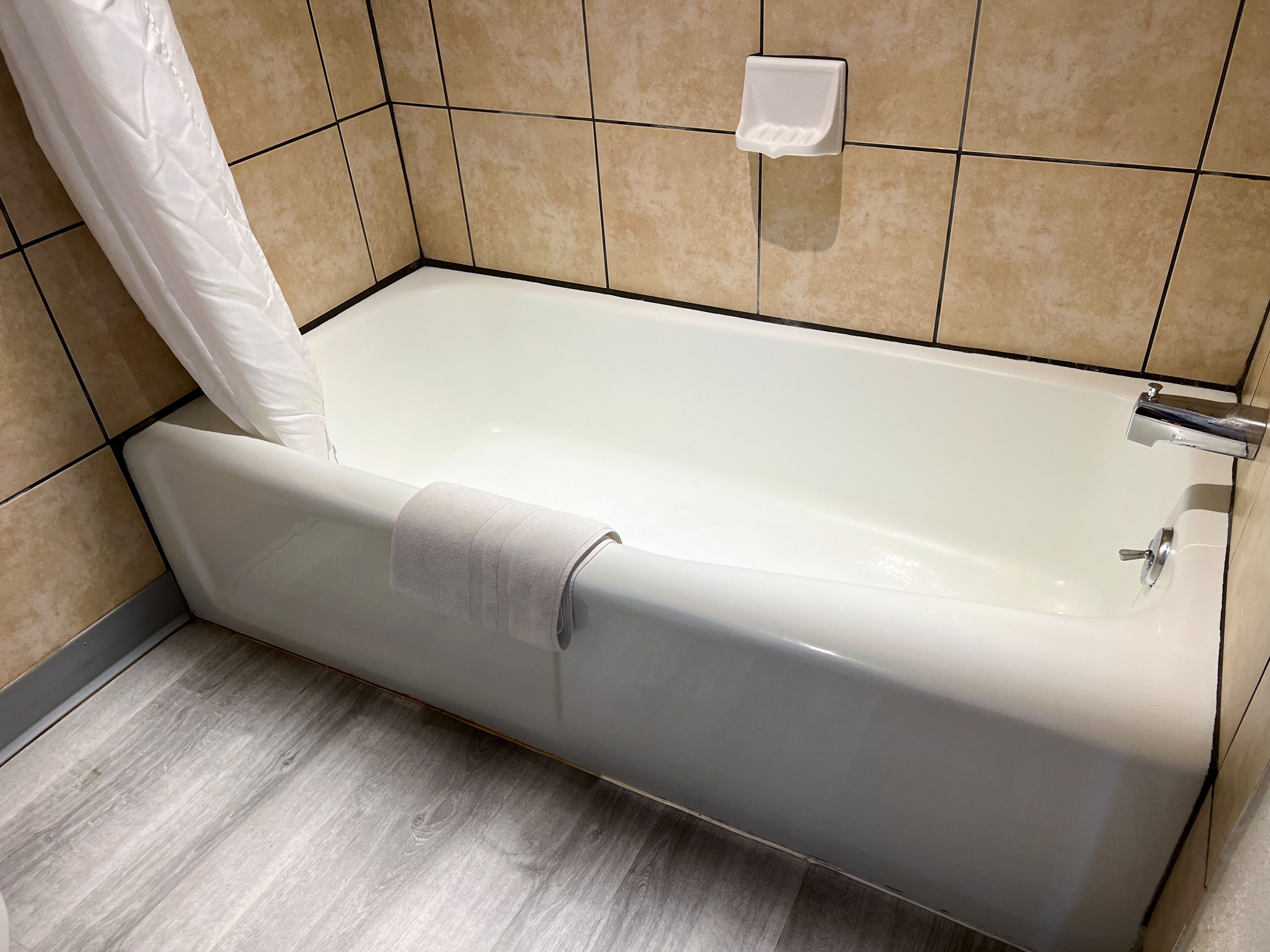 Et moderne badeværelse med badekar, håndklædestang og toiletpapirsholder på væggen.