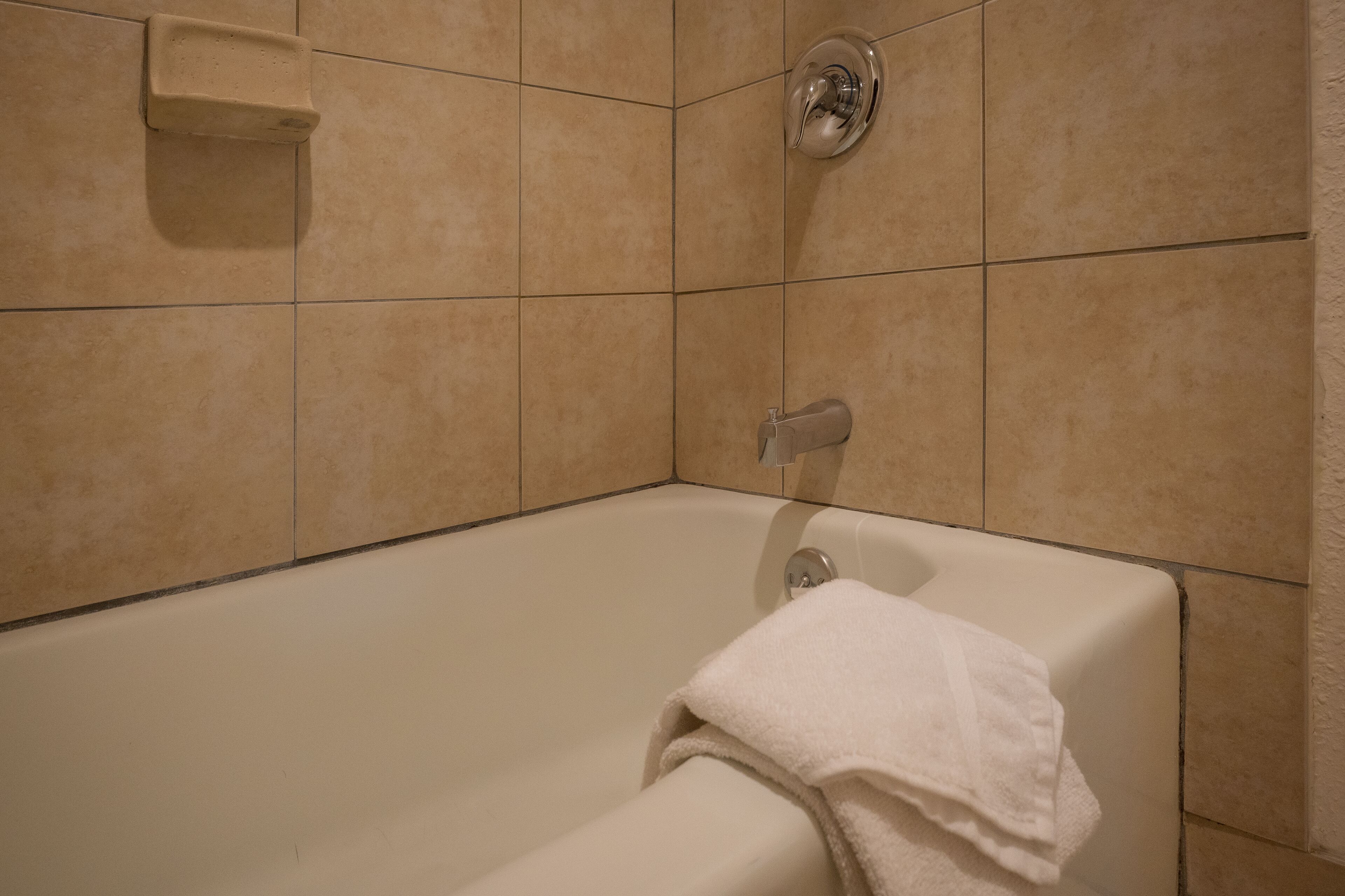 A bathroom with a bathtub, a towel, and a showerhead.