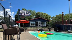 Un motel doté d’une piscine, de chaises longues et d’un panneau indiquant qu’il y a des chambres disponibles.