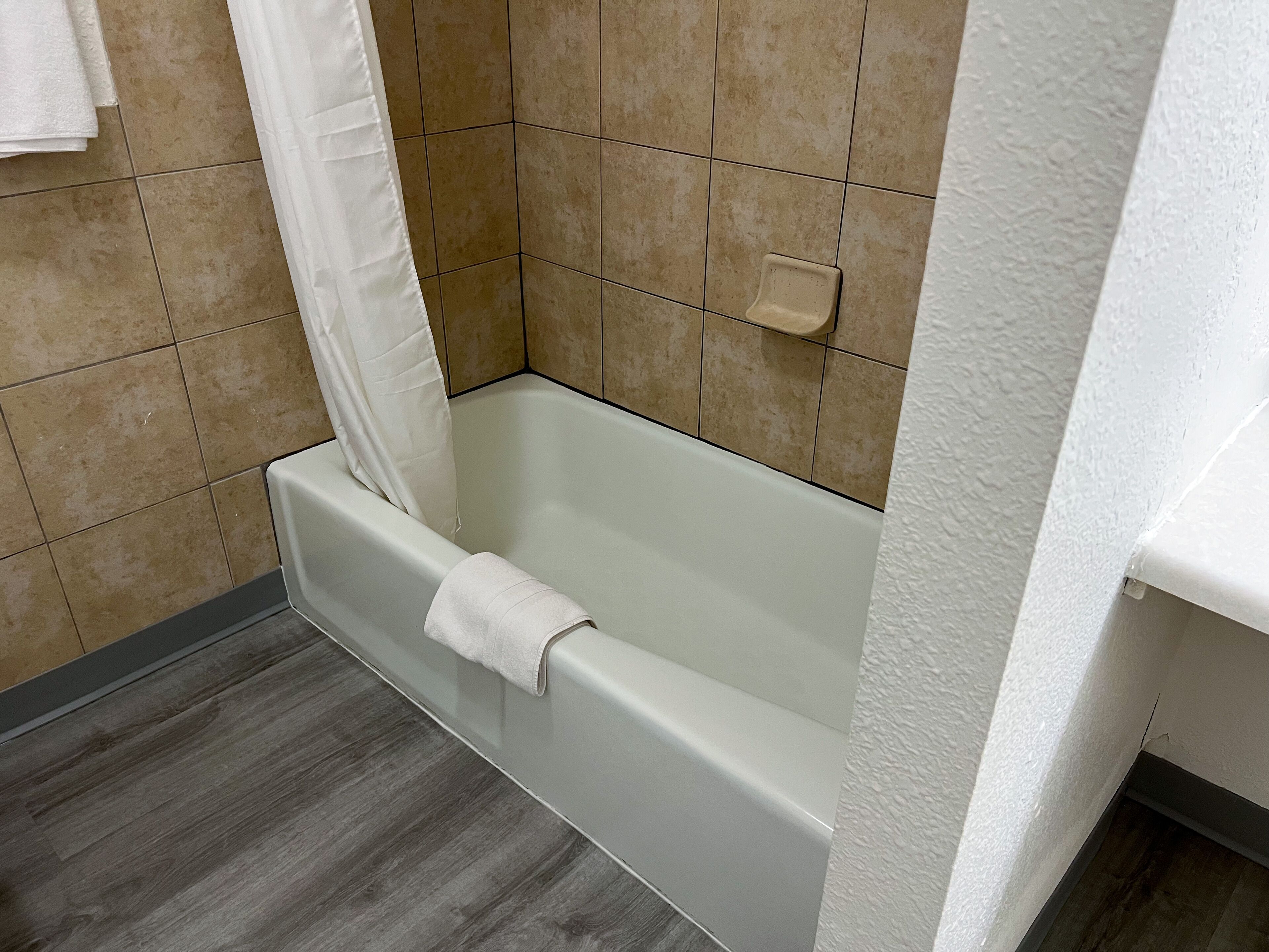 Ein Badezimmer mit einer Badewanne, einer Duschkabine und einem Seifenschälchen an der Wand.