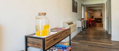 A hallway with a wooden bench, a glass pitcher of orange juice, and a vintage clock on the wall.