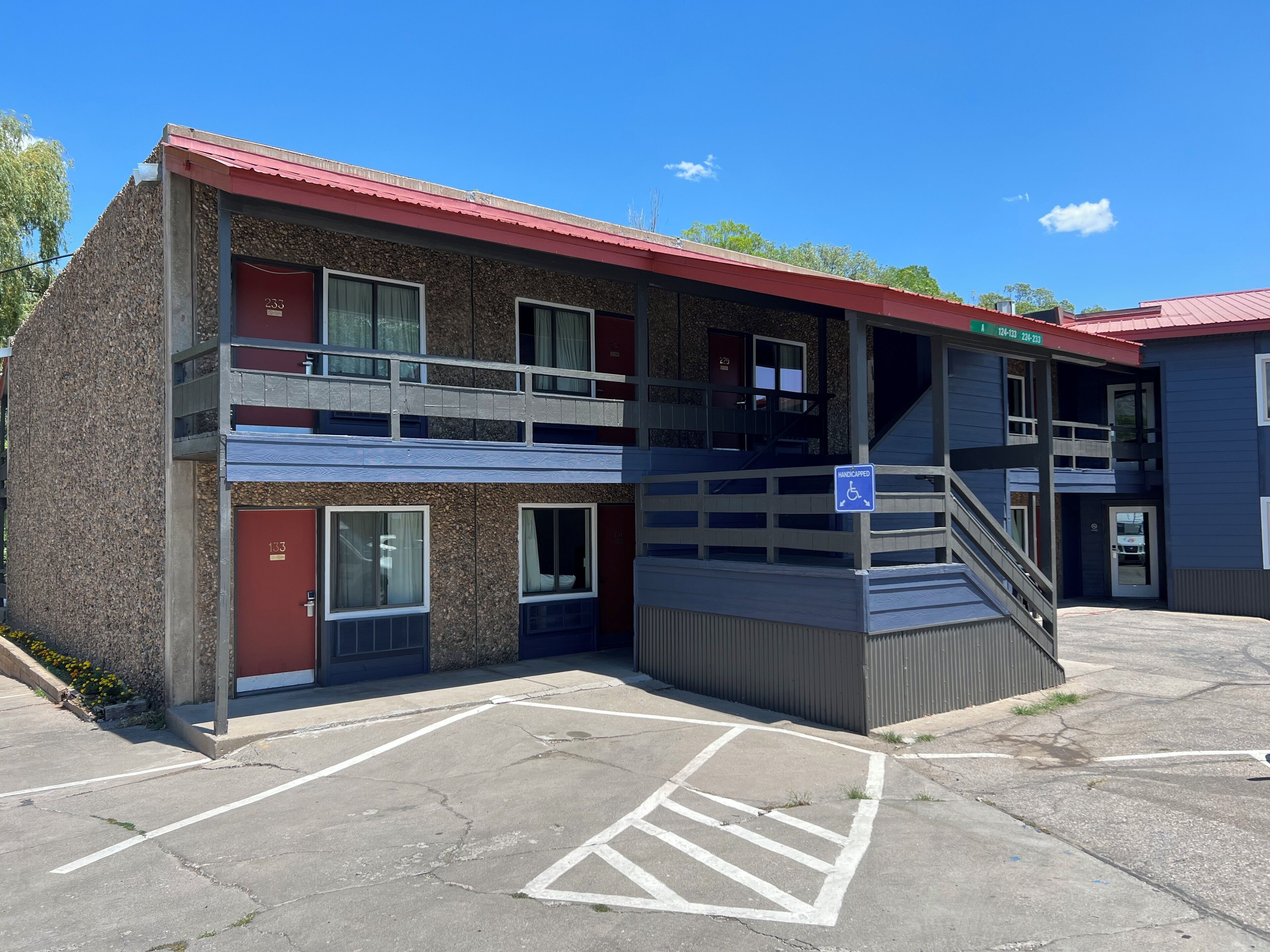 A two-story motel with a red roof, a handicap-accessible ramp, and a parking lot.