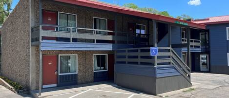A two-story motel with a red roof, a handicap-accessible ramp, and a parking lot.
