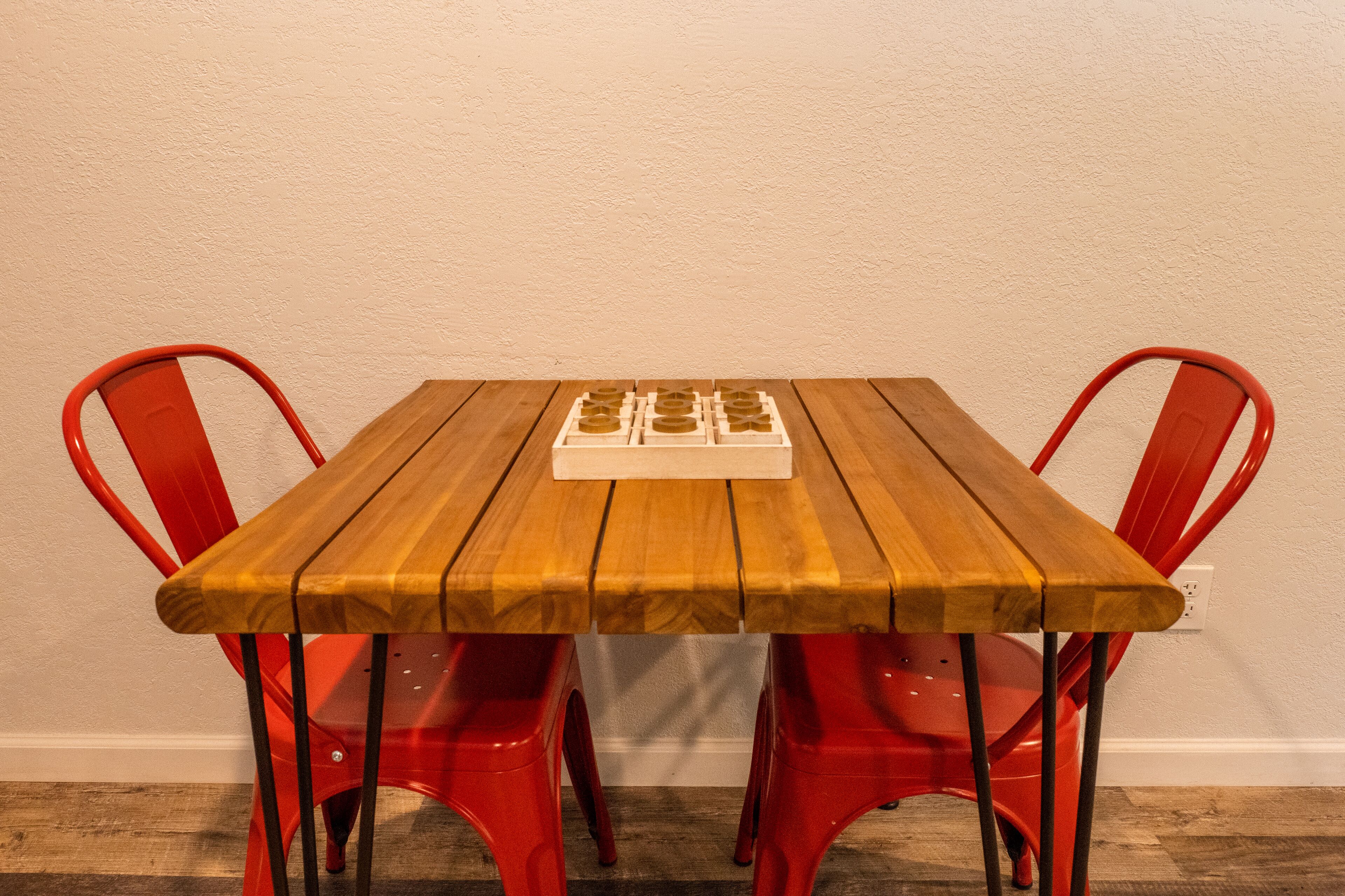 Un tavolo di legno con un sottopiatti bianco, circondato da sedie rosse.