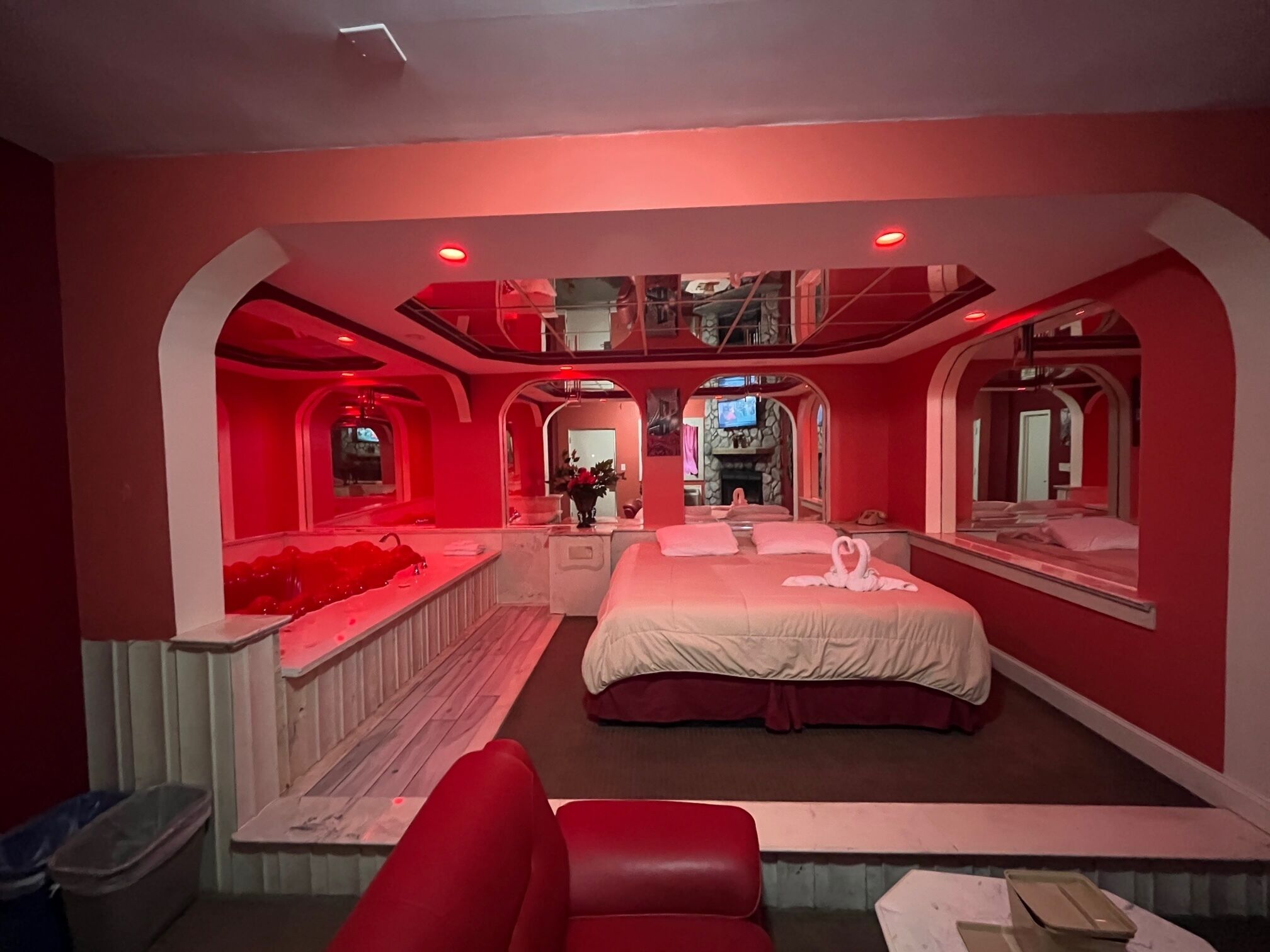A bedroom with a large bed, a red sofa, and a TV.