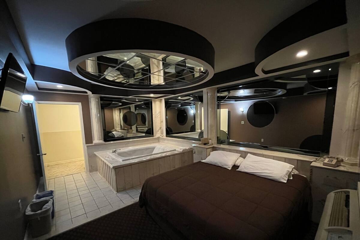 Una habitació d'hotel moderna amb un llit gran, una banyera separada i un mirall ampli.